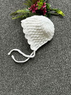 a white crocheted hat with flowers on the side and a string attached to it