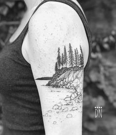 a black and white photo of a woman's arm with trees on the shore