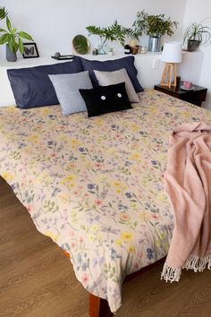 a bed with pillows and blankets on top of it in a room filled with potted plants