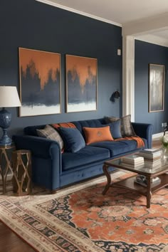 a living room with blue couches and orange pillows on top of the rugs