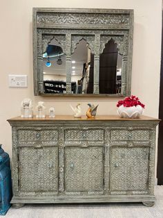 an ornately decorated dresser with mirror and vases on it's sideboard