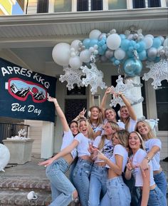 a group of young women standing next to each other in front of a building with balloons