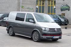 a grey van is parked in front of a building with several other cars behind it