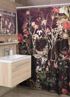 a bathroom with a floral shower curtain next to a sink