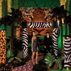 a man and woman standing in front of an animal themed stage with lights on it