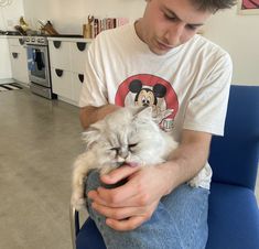 a man sitting in a chair holding a cat