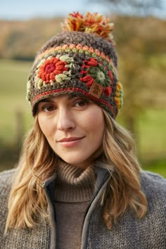 a woman wearing a knitted hat with pom pom on the top and side