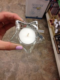 a person holding a small glass candle in their hand and some boxes on the ground