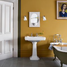 a bathroom with yellow walls and a claw foot bathtub in the center, an old fashioned sink on the far wall