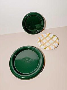 two green plates sitting next to each other on a white counter top with a yellow and white checkered napkin