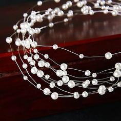 a close up of a string of pearls on a wooden table with other items in the background