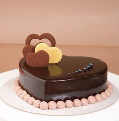 a heart shaped chocolate cake sitting on top of a white plate with beads around it