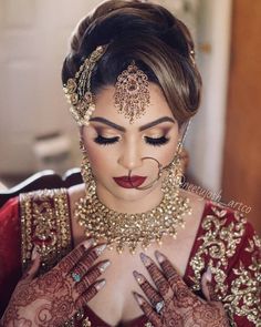 a woman in a red and gold bridal outfit with her hands on her chest