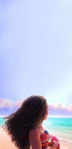 a woman sitting on top of a beach next to the ocean