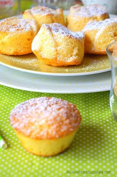 powdered sugar covered muffins sit on plates next to a glass of water