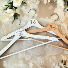 three wooden hangers with the names of two brides and one groom on them