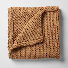 a brown knitted blanket folded on top of a white wall