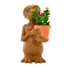 a clay figure holding a potted plant with flowers in it's hands and eyes wide open