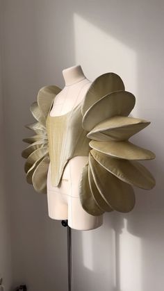 a white mannequin with large leaves on it