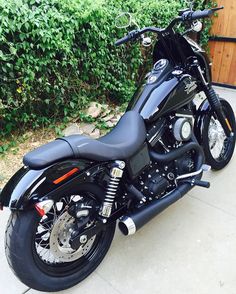 a black motorcycle parked in front of some bushes