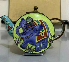 an elephant painted teapot sitting on top of a table