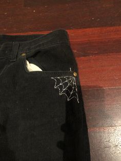 a pair of black cordon pants with spider webs on the front and side