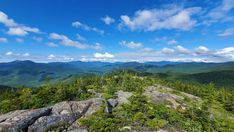 a view from the top of a mountain looking down at some trees and mountains in the distance