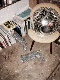 a disco ball sitting on top of a wooden chair next to a pile of books