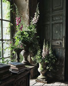 two vases filled with flowers sitting on top of a wooden table next to an open window