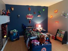 a child's bedroom with captain america decorations on the wall and toys all over the bed