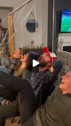 a group of people sitting in a living room watching something on the tv and laughing