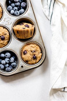 blueberry muffins in a metal tray with fresh blueberries on the side