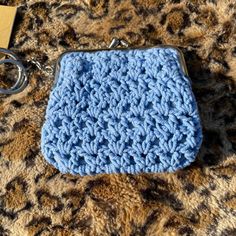 a blue crocheted purse sitting on top of a leopard print blanket next to a pair of scissors