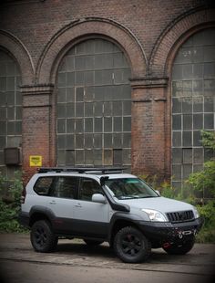 a grey suv parked in front of an old brick building