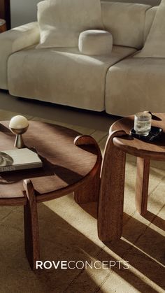 two wooden tables sitting on top of a floor next to a couch and coffee table