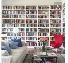 a living room filled with lots of books and furniture next to a wall full of books