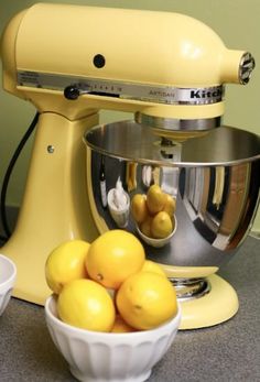 a yellow mixer and bowl filled with lemons