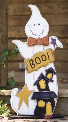 a wooden sign that says boo with a house on it and a ghost in the background