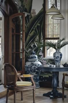 a living room filled with furniture and large potted plants on top of a table