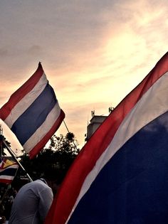 two flags are flying in the air with people watching from the sidelines behind them