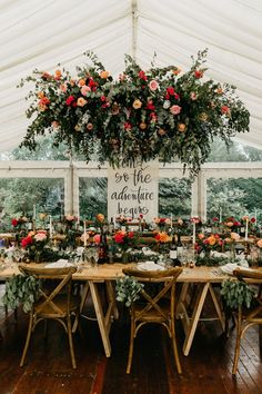 a table with flowers and greenery is set up in a tent for an event