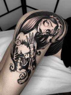 a woman's leg with a black and white tattoo design on her thigh, holding a knife