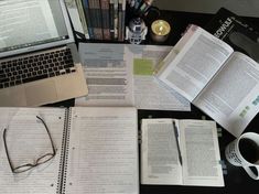 an open book sitting on top of a desk next to a laptop and coffee cup