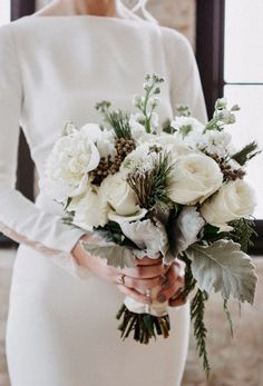 a woman holding a bouquet of white flowers