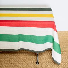 a striped table cloth on top of a wicker place mat with black metal legs