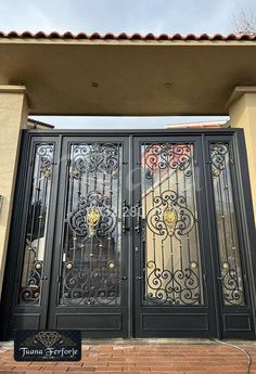 an iron gate with decorative designs on the top and bottom part, in front of a house