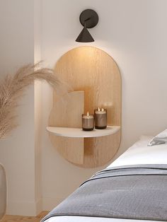 two candles are lit in front of a circular shelf on the wall next to a bed