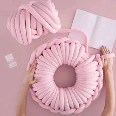 a woman is holding a pink pillow with a spiral design on it next to an open book