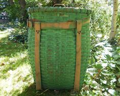 a large green basket sitting in the grass