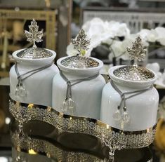 three white glass jars with silver decorations on them